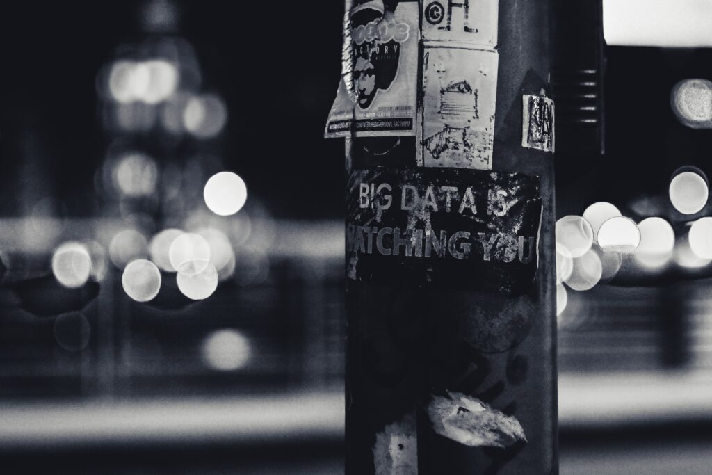 Sort/hvitt foto av en lyktestolpe med diverse plakater på, inkludert ordet Big data som symboliserer digitalisering. 