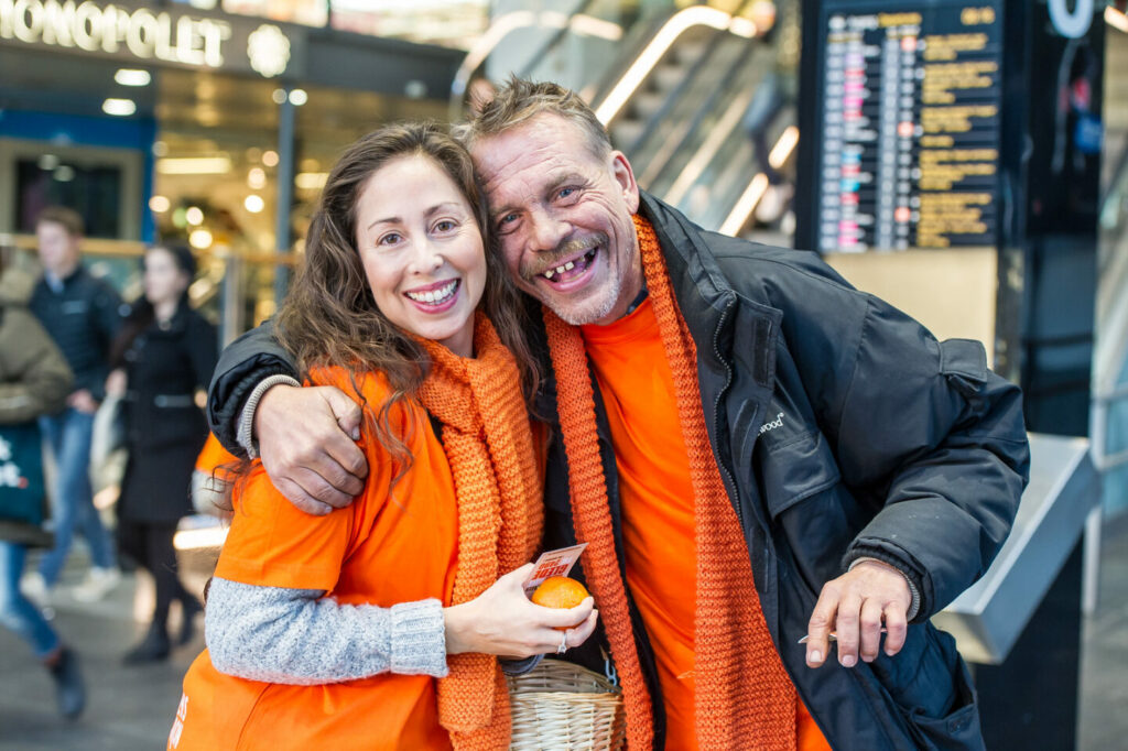 To smilende personer med oransje skjerf